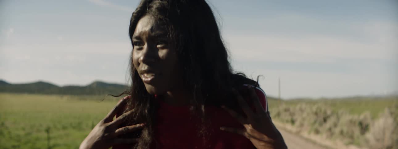 A woman gestures wildly with her hands then smiles and twirls with her hands to her head