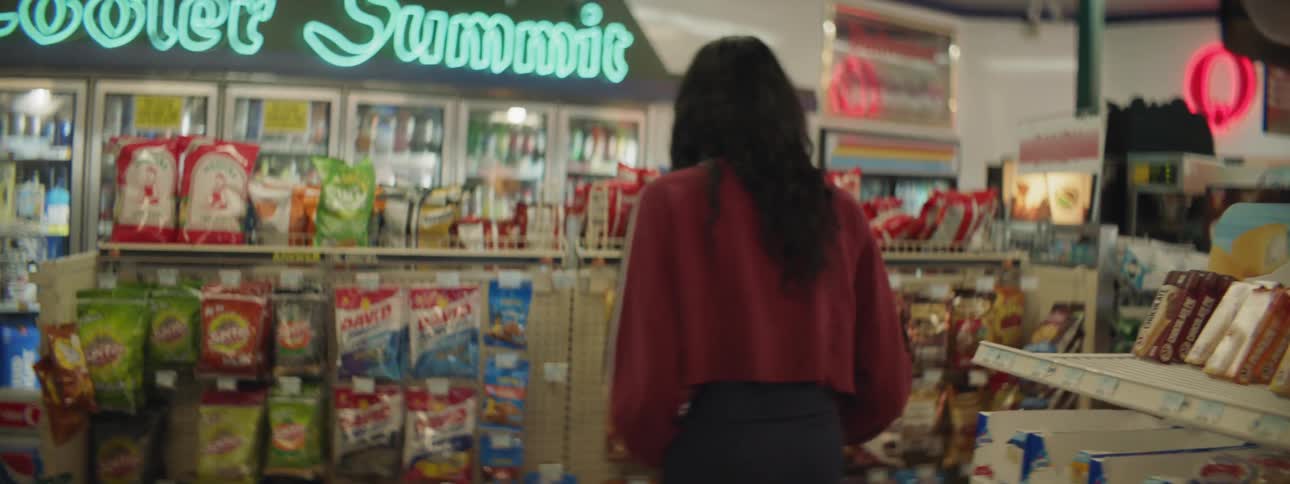 A woman smiling as she picks up snacks in a store