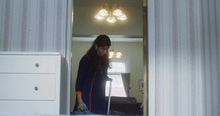 Woman opens the door picking up her bag and pulling her suitcase
