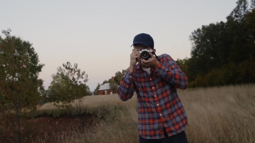 A man smiles and takes two pictures with his camera