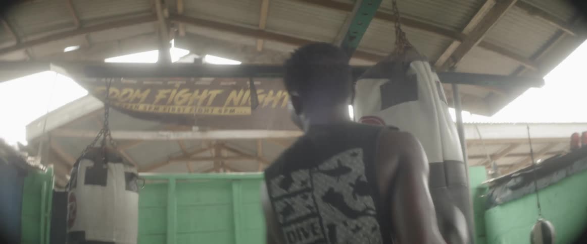 Man wearing boxing gloves walking around punching bags