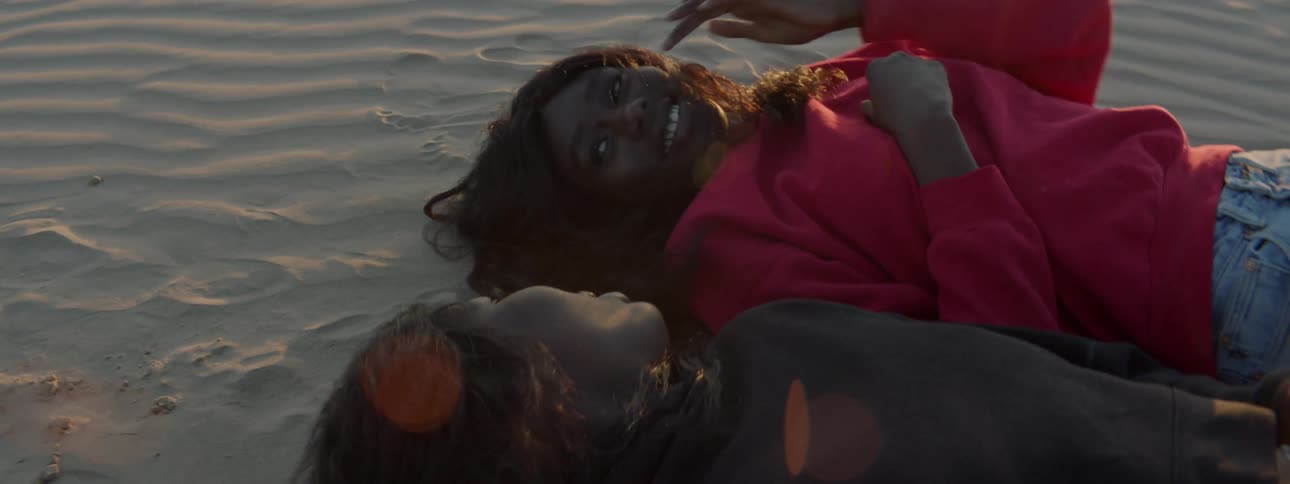 Two women laughing together while laying on the beach