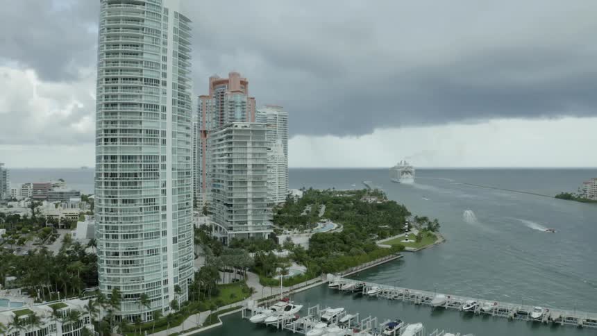 A large boat drives in the ocean next to a city