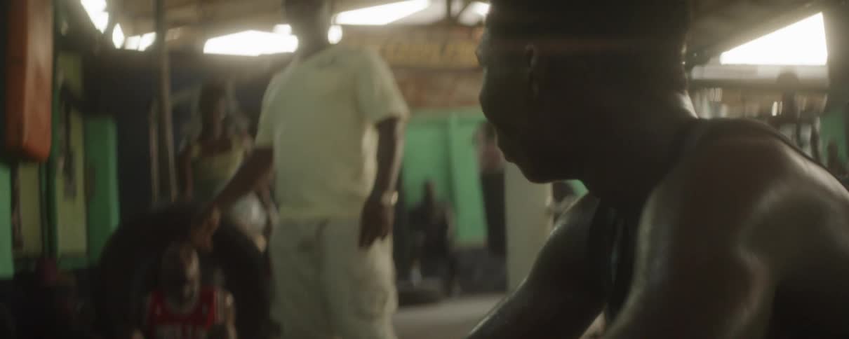A man talks to another man in a gym full of men