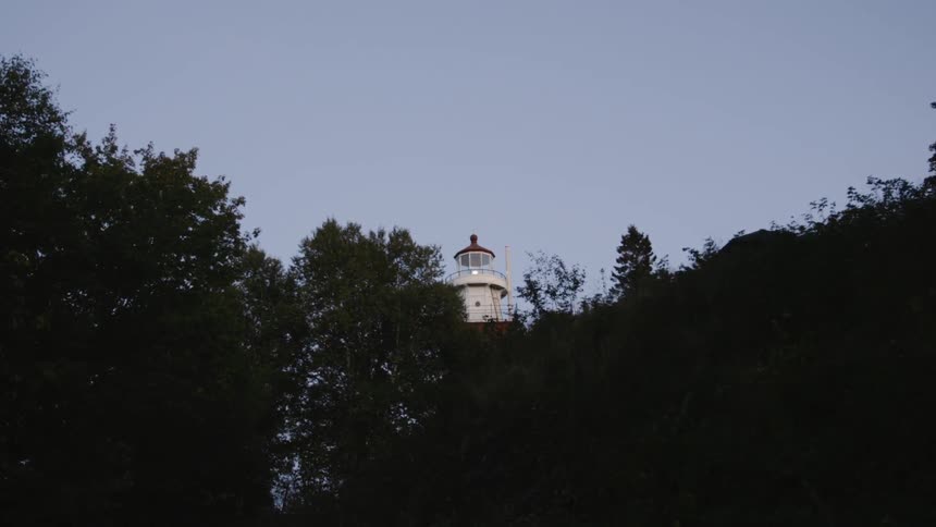 Looking through trees at a lighthouse during sunset