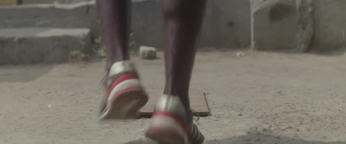 A man skips rope on the dirt alternating foots as he hops