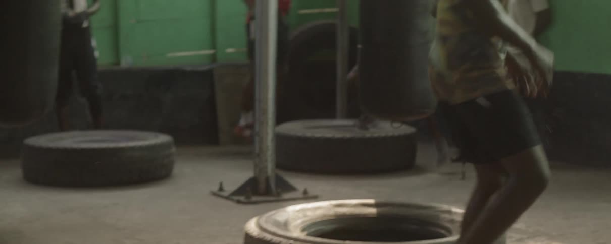 Men in a gym do exercises that involve jumping on tires