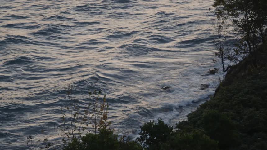 Waves slowly rolling around a sea next to the shore
