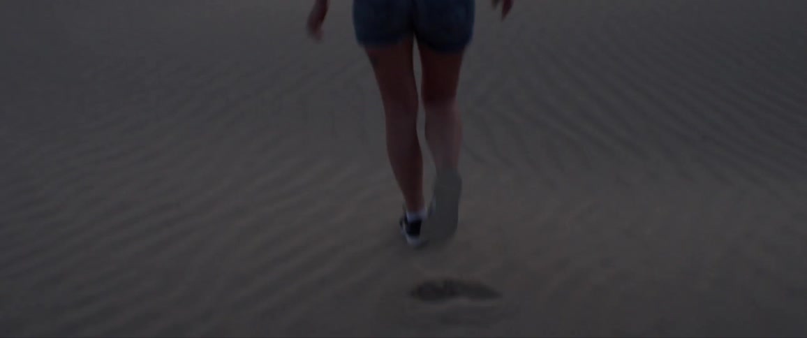 A woman is laughing walking across the sand