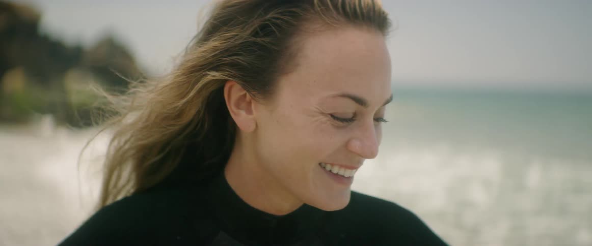 A woman smiling and giggling by the ocean