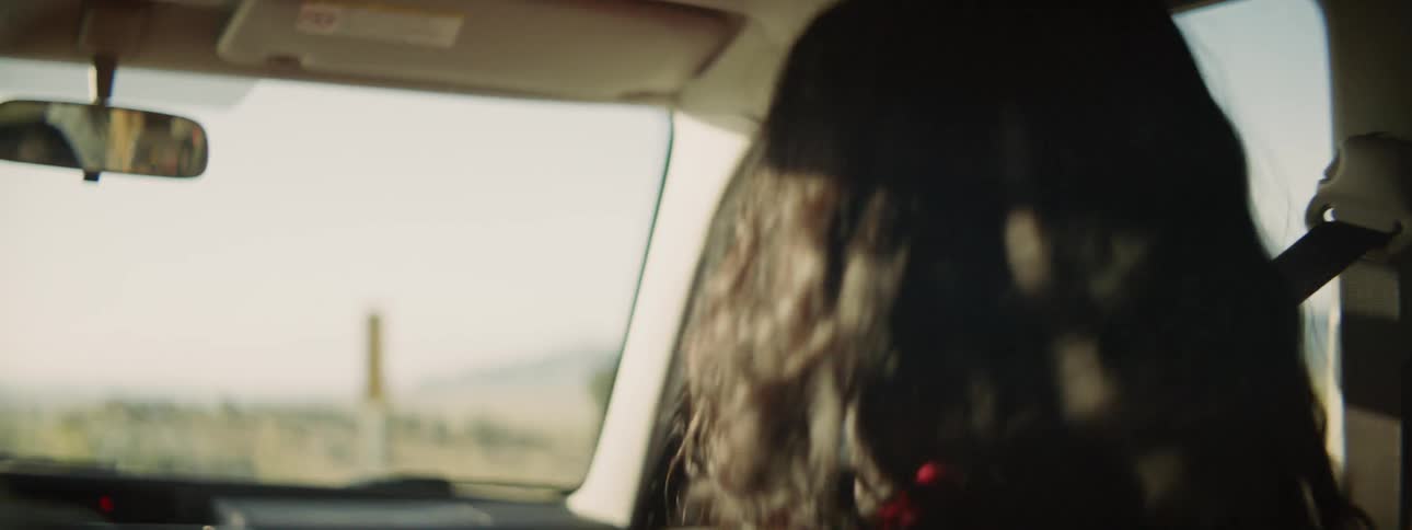 Woman singing and dancing in the passenger seat of a car