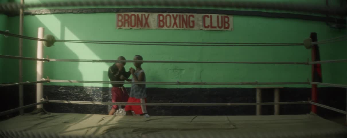 A young boy practices boxing while another boy practices a defensive pose in a boxing gym