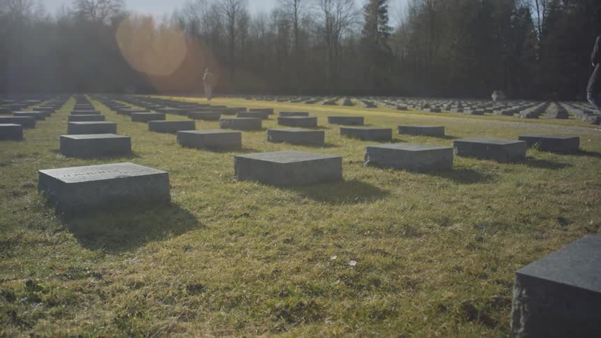 Two people walk through a large cemetery