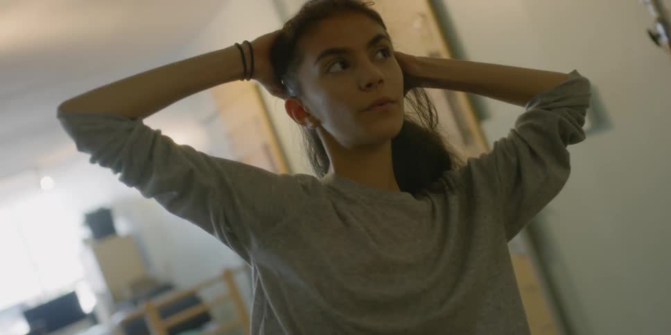 A woman bending slightly to the side with arms behind her head