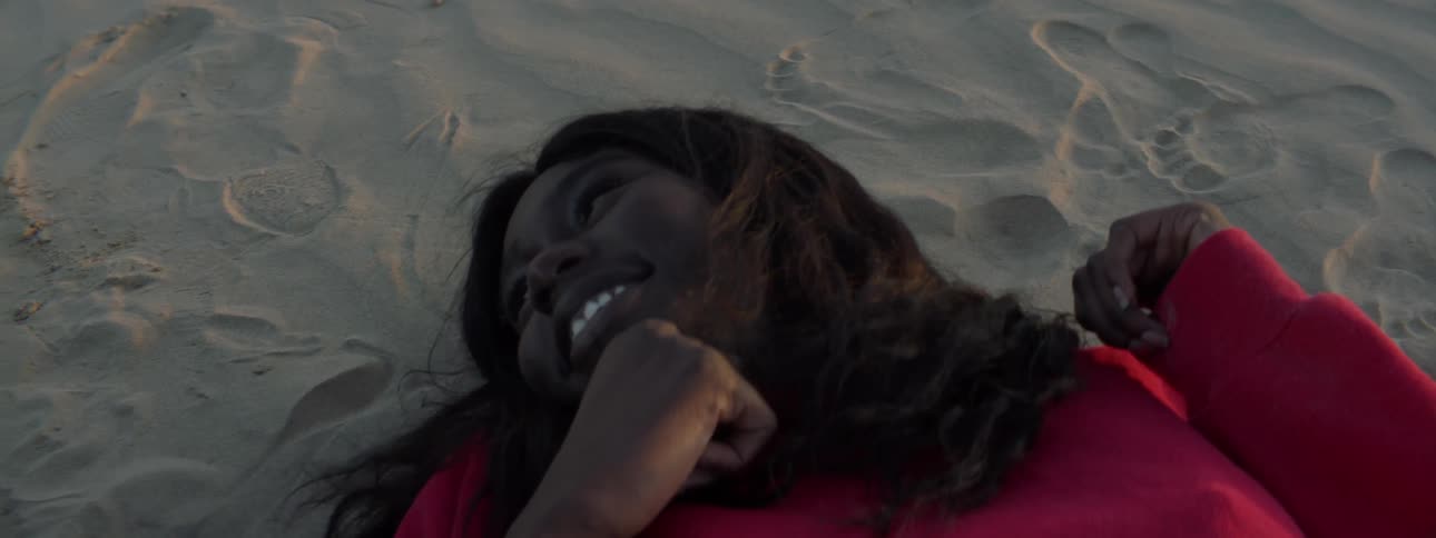 Two females laying on the beach talking to each other