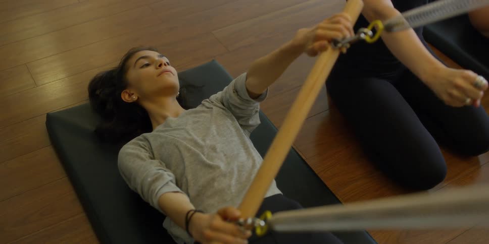 A female laying on a mat grasping a training bar above her
