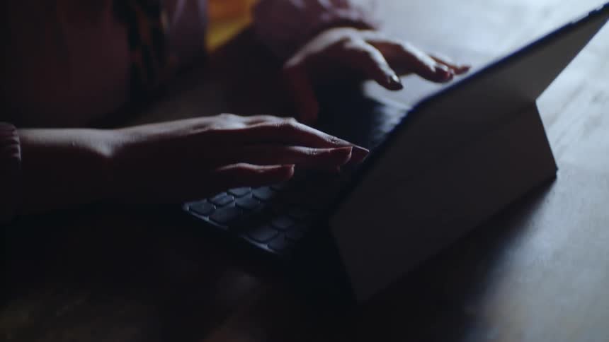 Woman types on a keyboard sitting at a table