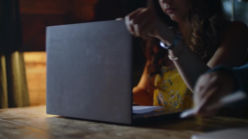 A group of people with devices sit around a wooden table