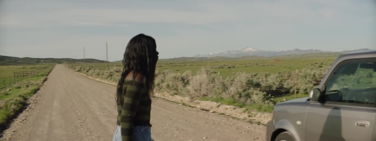 A woman gets out of a car and walks across the road pacing