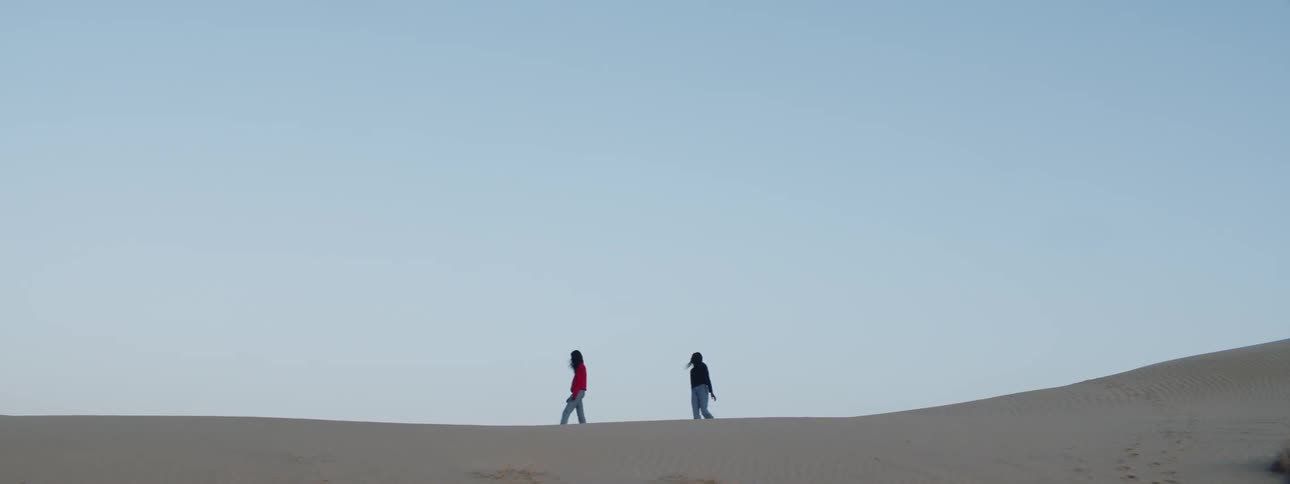 Two women walk in the sandy desert