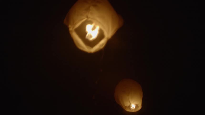 Paper lanterns float into the sky at night