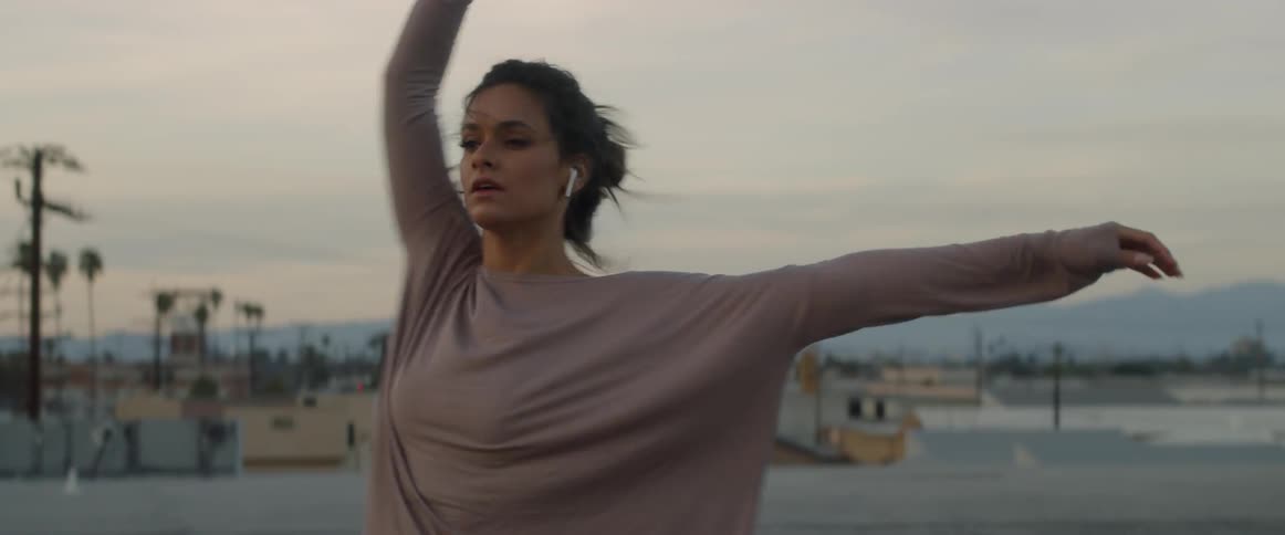 A woman dances in an empty lot as she wears wireless earbuds