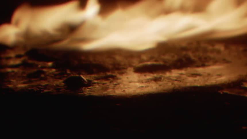 A fire burns outside at night