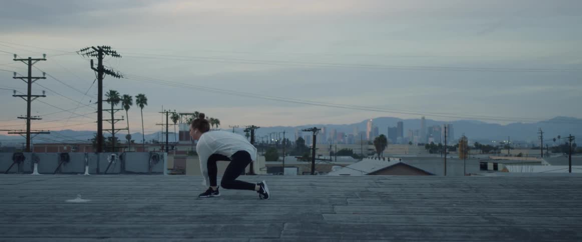 A female dancing in an area outside with a city view