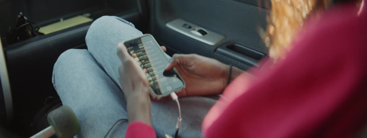 A person that is sitting in a car scrolling on their phone