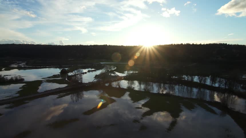 The sun shines over a body of water that reflects the sky