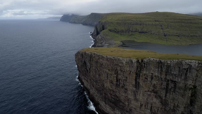 Waves are crashing against cliffs on a cloudy day