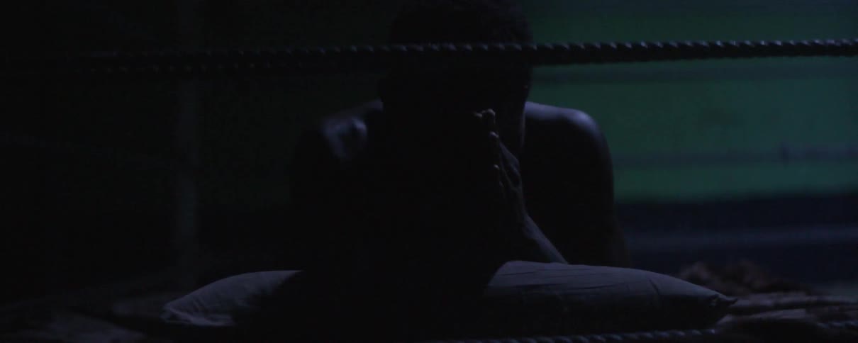 A man lays in a boxing ring and prays