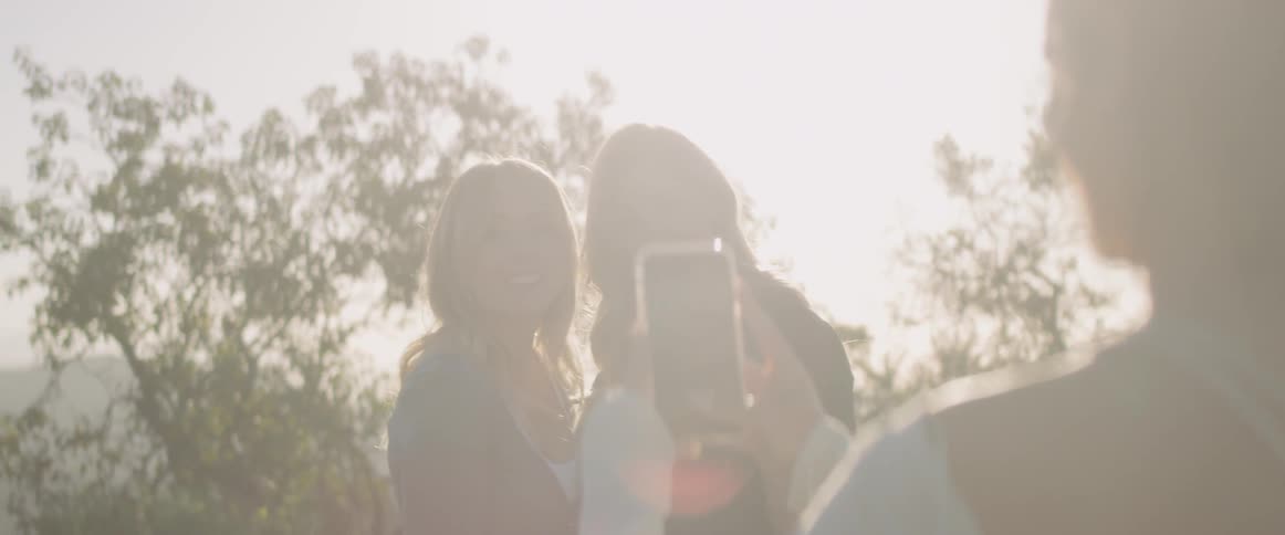 Woman takes a picture of two other women on a sunny day
