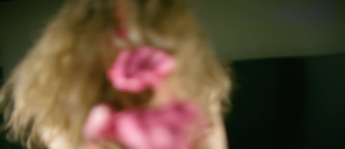 A woman with her hands painted pink is dancing inside in daylight