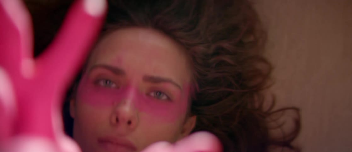 Woman with pink paint on her hands and face waves her arms around
