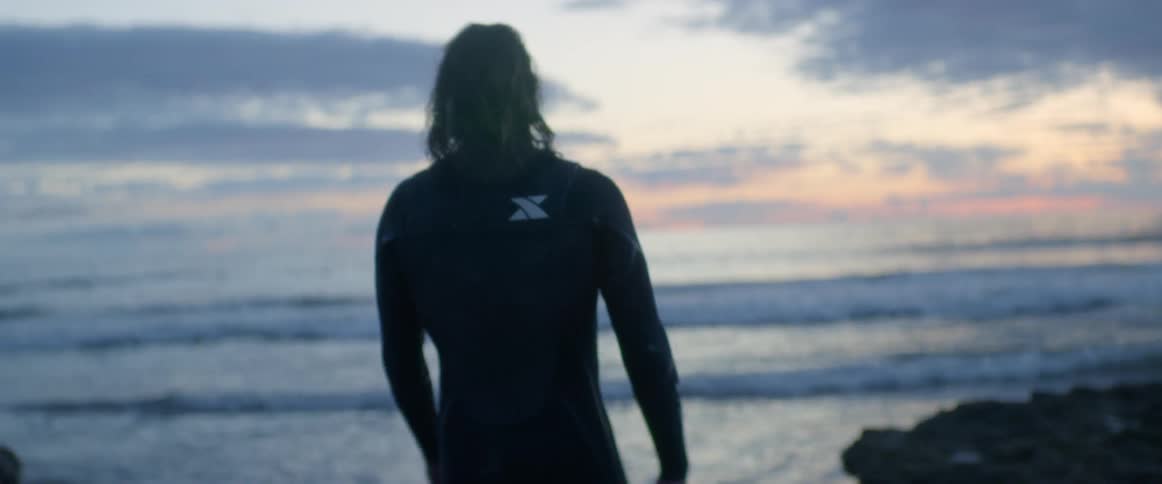 A surfer walks towards the water