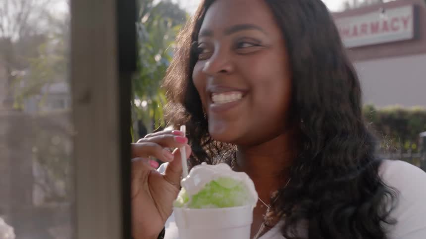 Woman sips a dessert out of a cup on a sunny day