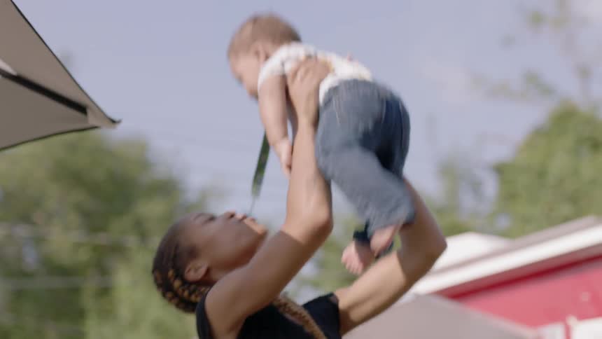 Woman smiles and tosses a child in the air