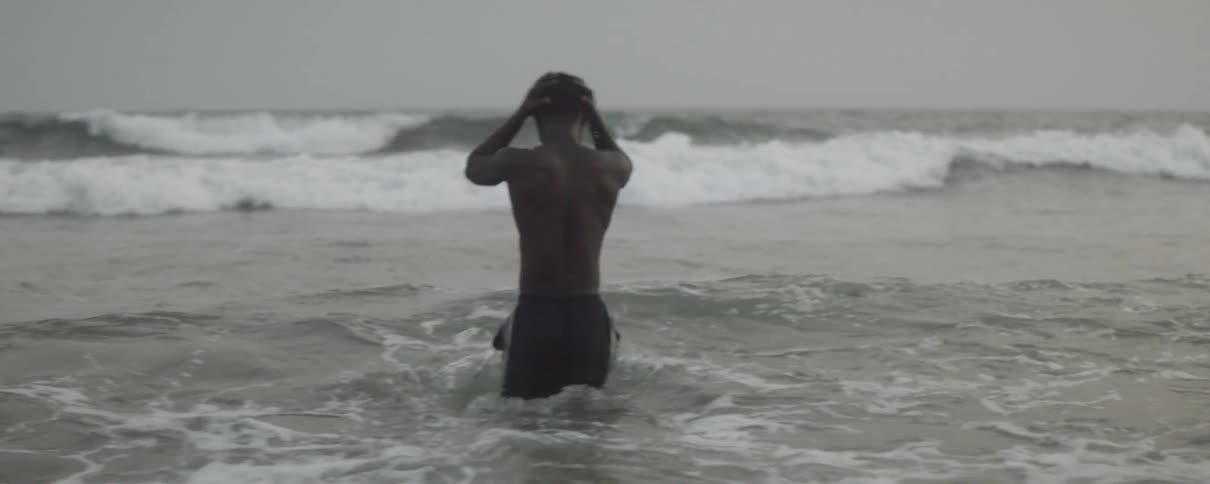 A man walks through the waves of the ocean before diving and swimming