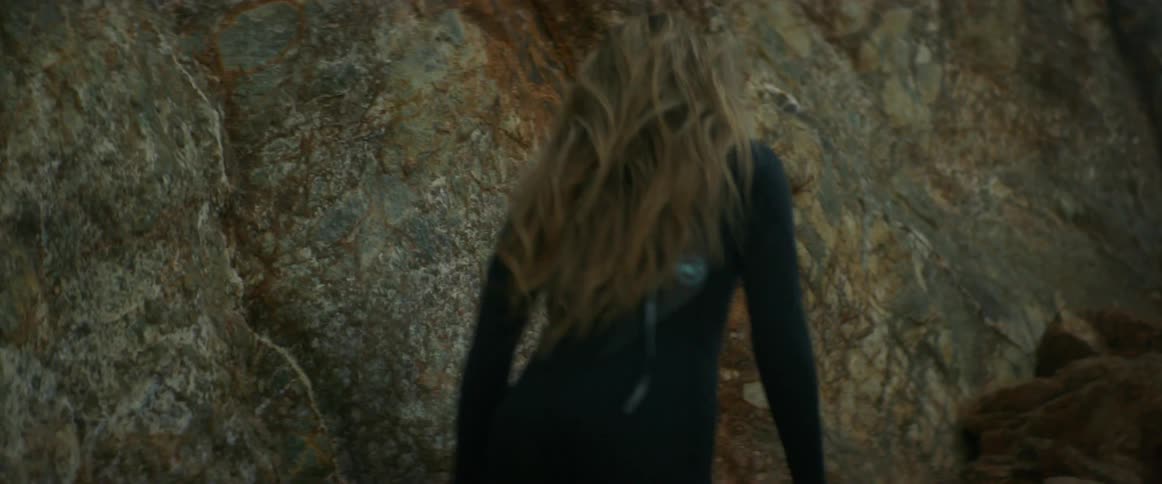 Woman wearing scuba gear walking up a cliff