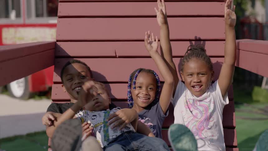 Four children are sitting on a chair outside