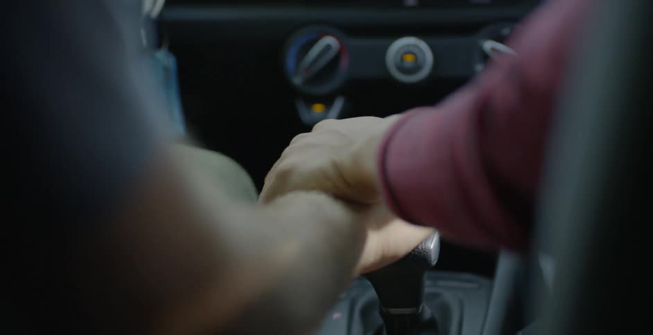 A woman grabbing a man's hand while driving