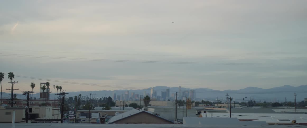 A downtown of a city is seen at dusk with mountains seen in the distance