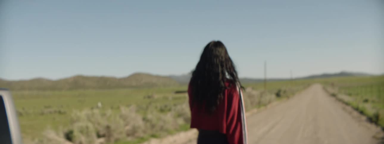 Woman angrily walking down the middle of a dirt road