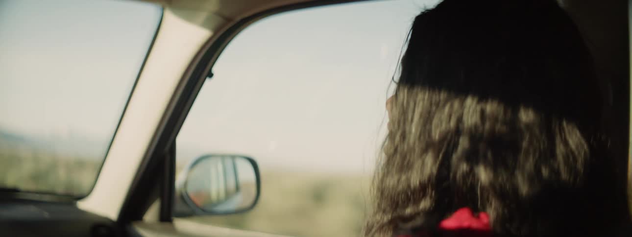 Woman smiles and talks in a car on a sunny day