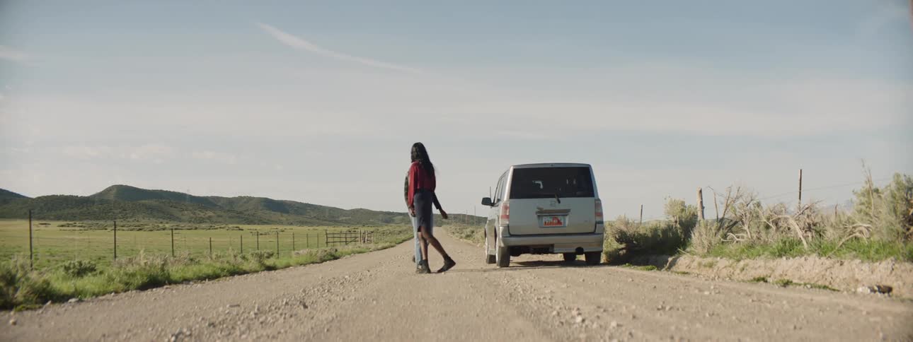 Two people arguing in the middle of the road next to a vehicle