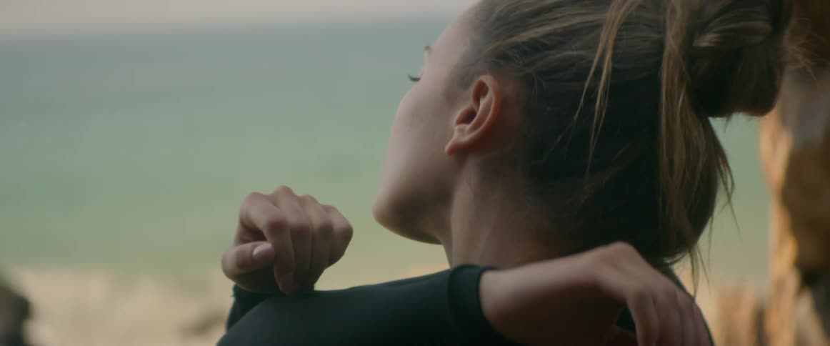 Woman surfer stretching her arms on the beach