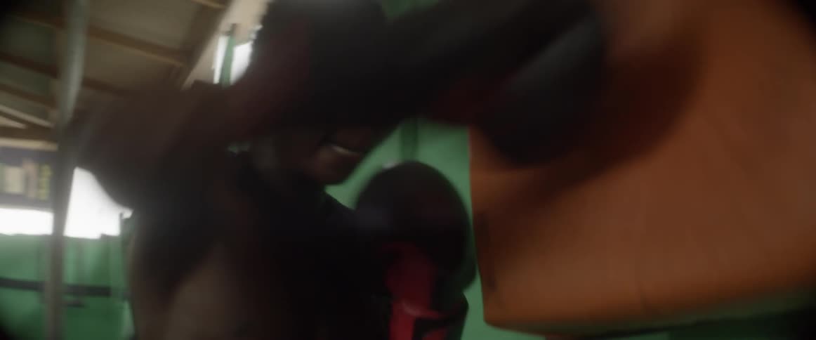 A teenage boy is practicing boxing punches in an old dreary gym
