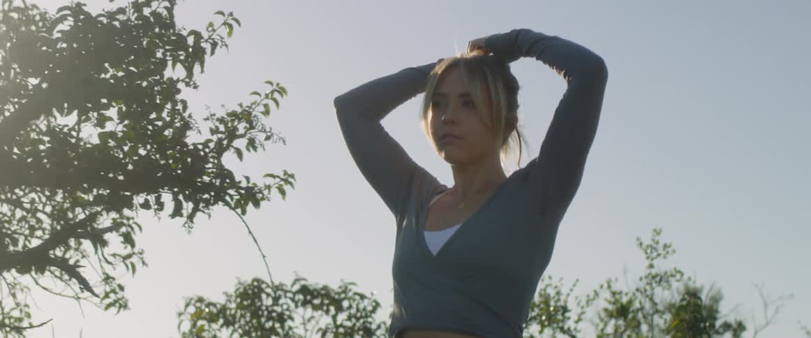 Woman tying her hair outdoors on a bright and sunny day