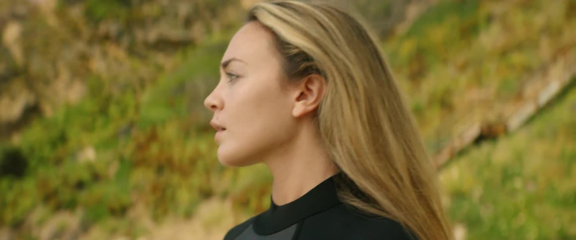A woman fixes the strap on her wetsuit